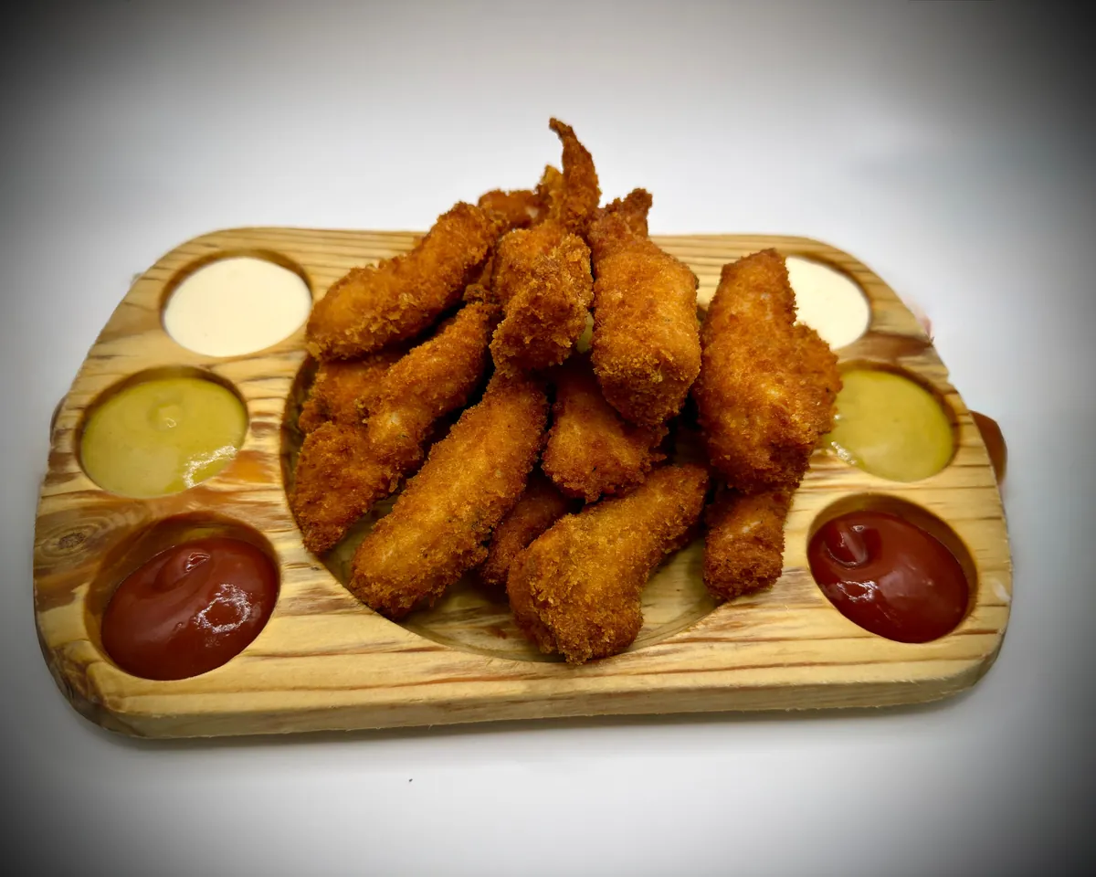 Fingers de pollo con cuatro salsas sobre tabla de madera