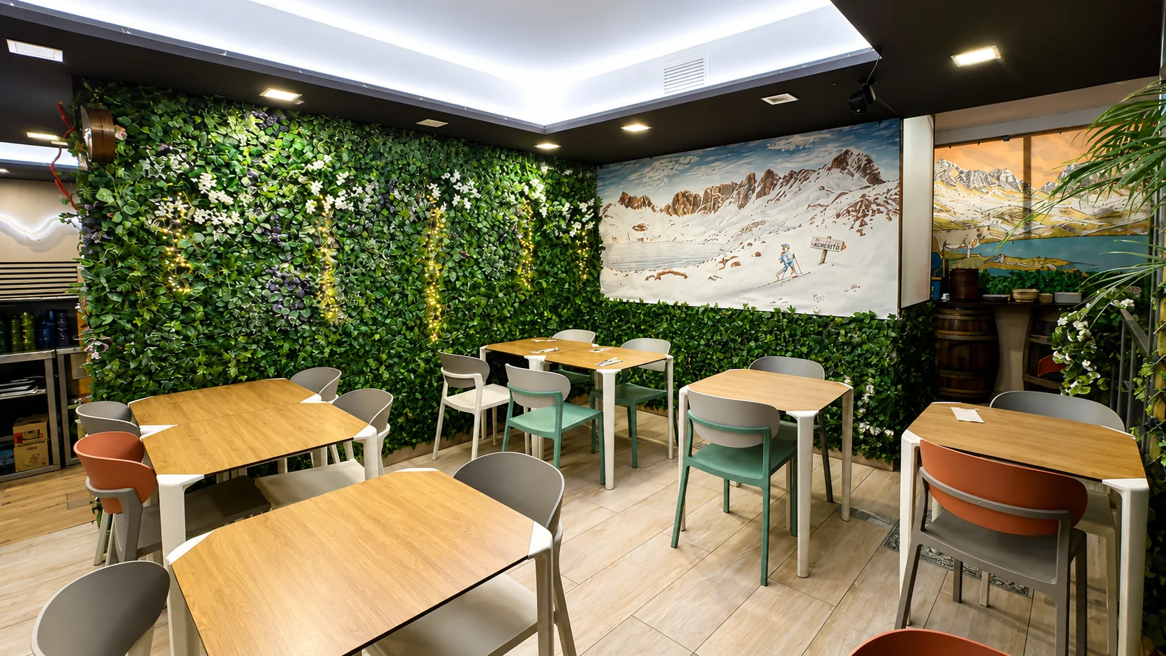 Comedor con pared vegetal y mural del Pirineo